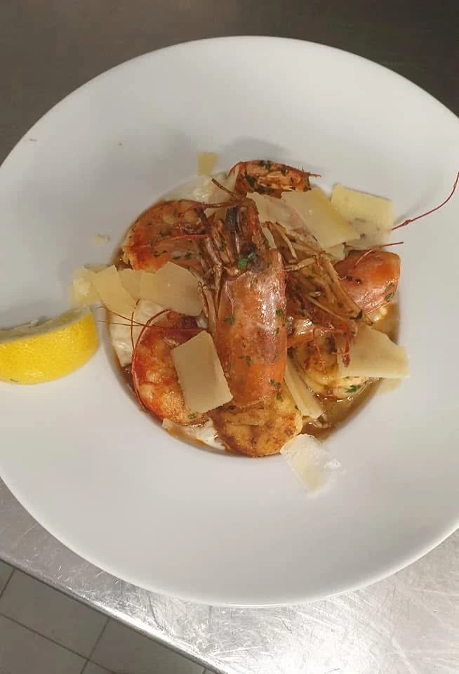 Assiette de gambas avec copeaux de fromage et citron.